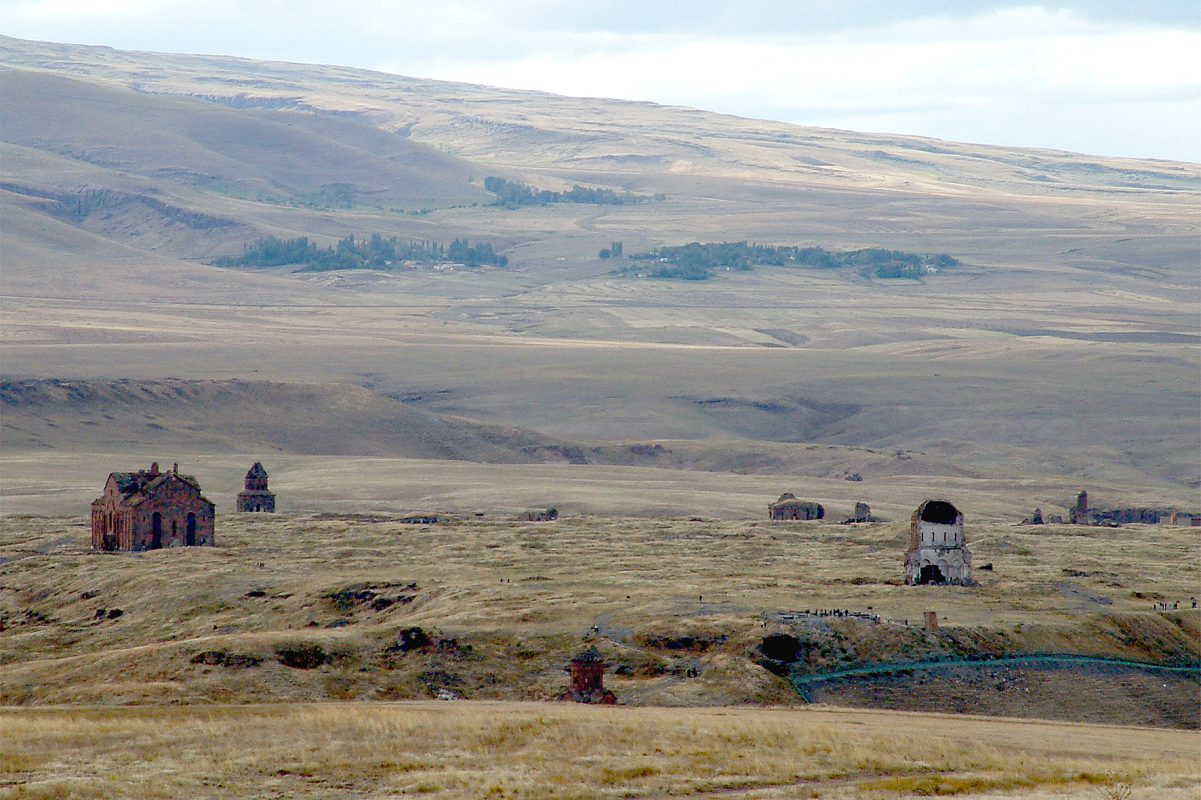The ruins of Ani as seen from the Armenian side. The <a href="/content/Cathedral_of_Ani" style="color:blue">cathedral</a> with its missing dome is seen on the left, the half-collapsed Church of the Holy Redeemer on the right.